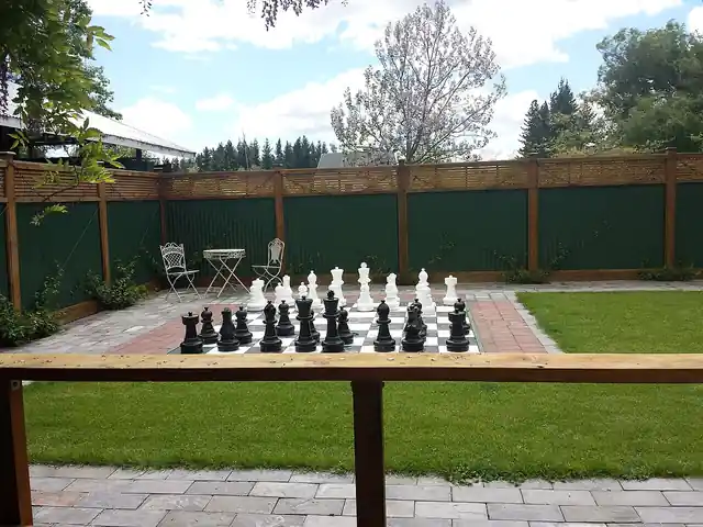 Large chess pieces arranged on an outdoor chessboard.
