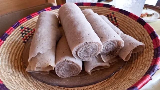 Rolled injera flatbreads arranged in a basket.