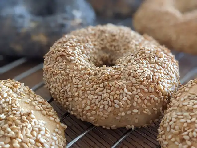 Sesame-coated bagels cooling on a wire rack.