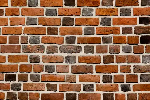 A close view of red and brown brickwork with mortar joints.