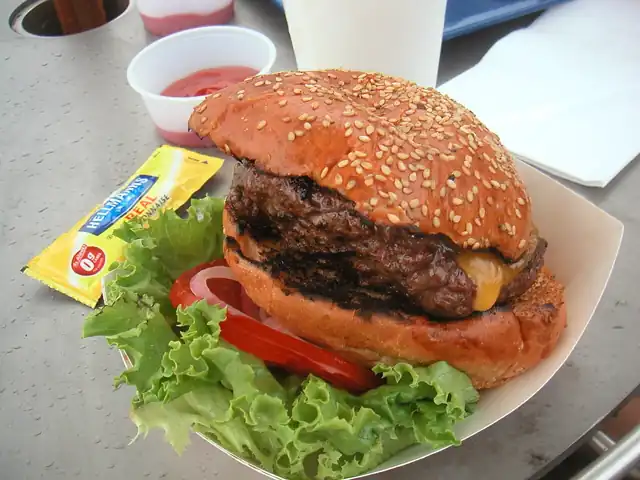 A burger with cheese and salad in a sesame-seed bun.