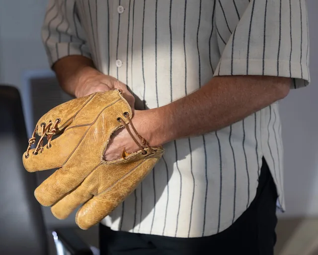 A worn leather baseball glove held in two hands.