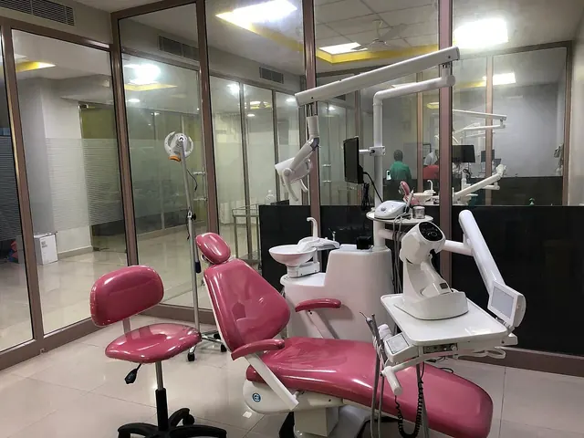 An unoccupied pink dental chair with an examination lamp and dental equipment.