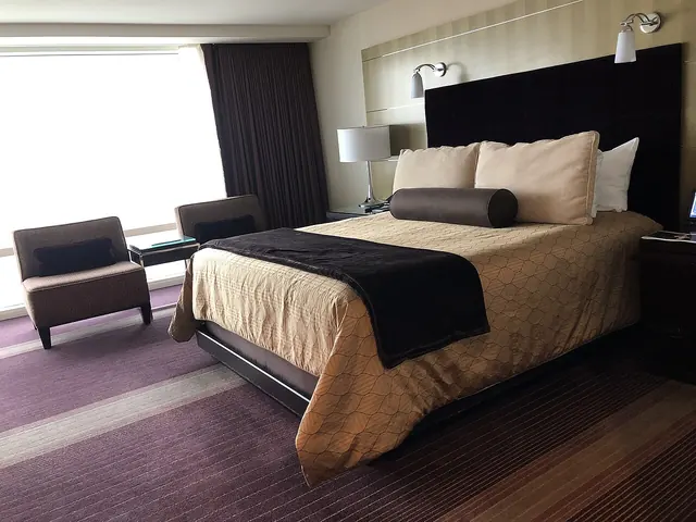 A hotel bedroom with a double bed, seating and a large window.
