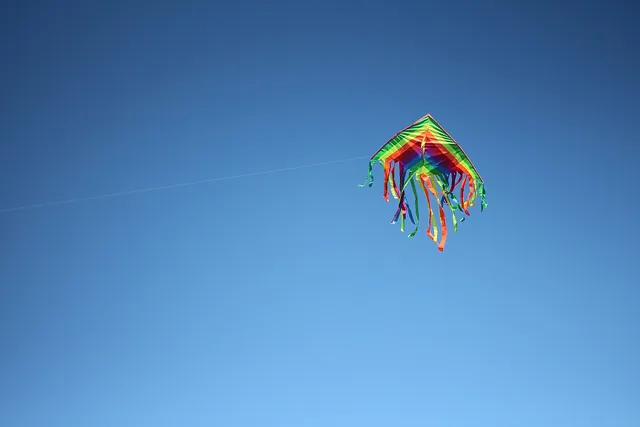 A colourful kite with ribbon tails against a clear blue sky.