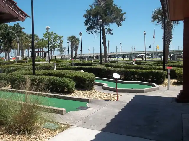 Small putting lanes bordered by low hedges at a miniature golf course.