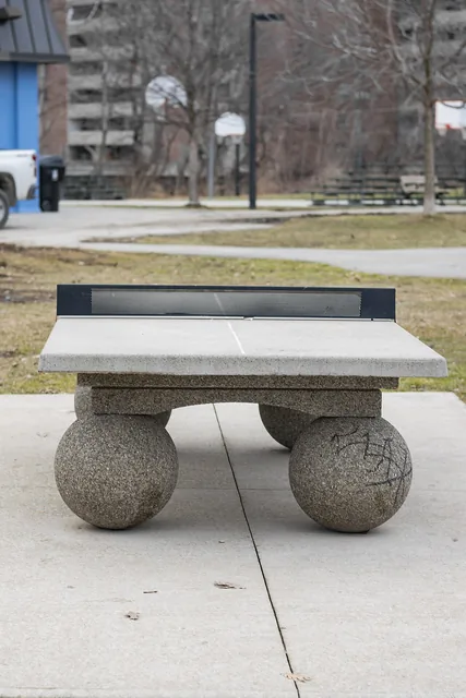 A concrete outdoor table tennis table with a metal net.