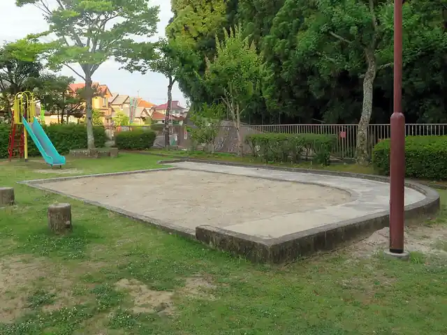 An empty sandbox with a low concrete edge beside a playground slide.