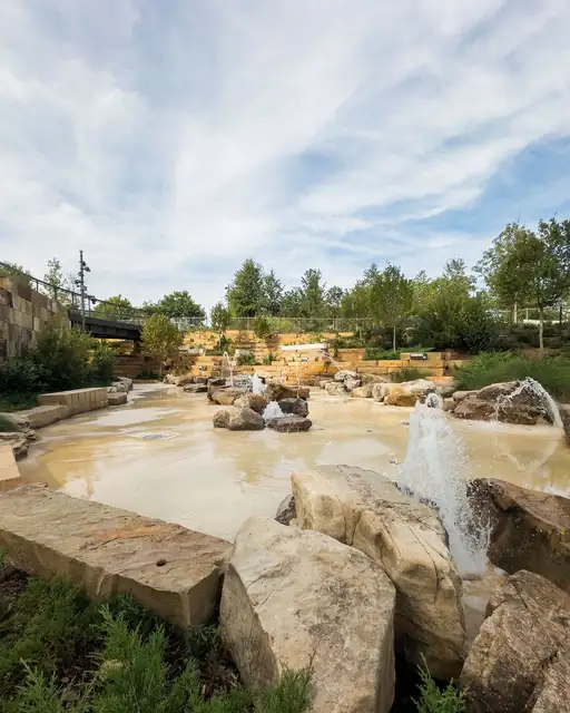 Water jets rising between rocks at an outdoor splash pad.