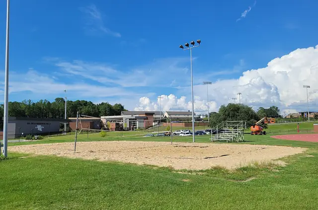 An outdoor beach volleyball court with sand, a net and floodlights.