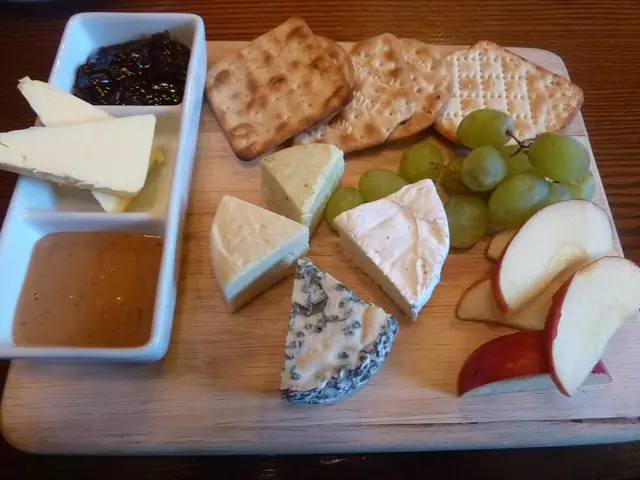 A selection of cheeses with crackers, grapes and condiments.