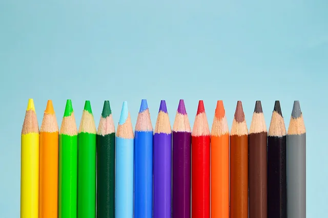 Sharpened coloured pencils arranged in a row against a blue background.