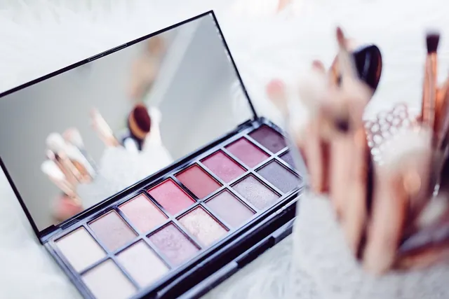 Makeup brushes beside an eye-shadow palette.