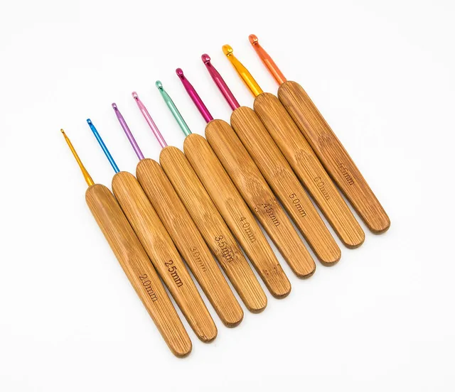Crochet hooks with wooden handles and coloured metal tips arranged by size.