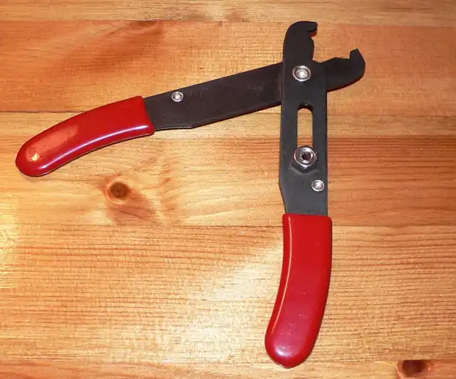 A red-handled wire stripper resting on a wooden surface.