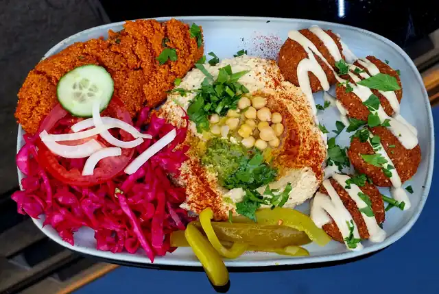 Falafel patties served with vegetables and a grain salad.