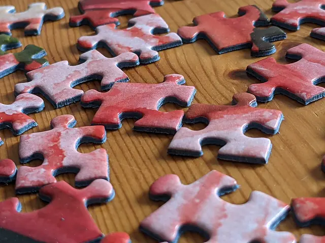 Red jigsaw puzzle pieces sorted on a wooden table.