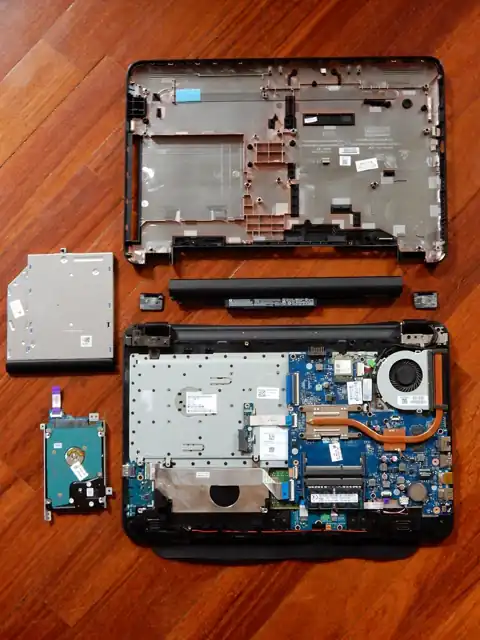 A disassembled laptop with its motherboard and other components exposed.