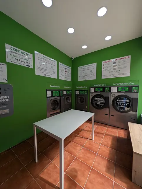 Self-service laundry machines and folding tables inside a laundromat.