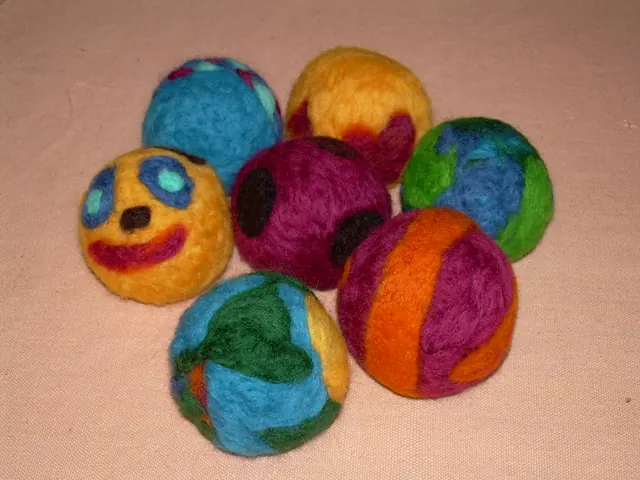 Colourful needle-felted balls decorated with simple faces and patterns.