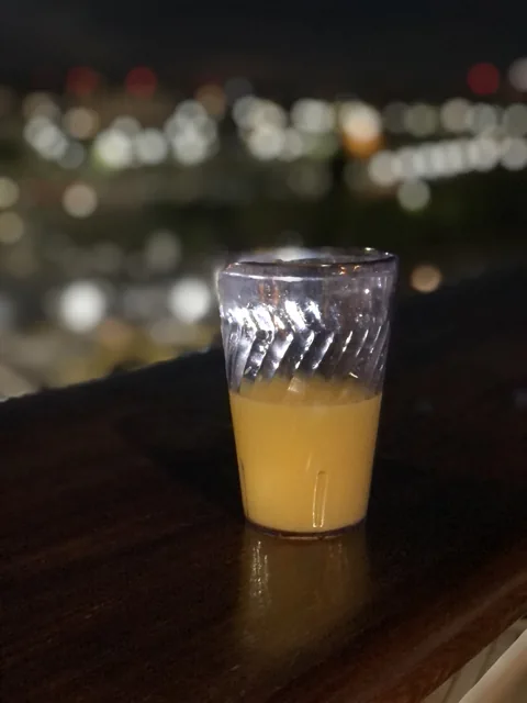 A glass of orange juice on a wooden counter.