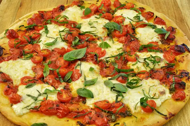Baked pizza with tomato, cheese and fresh basil.