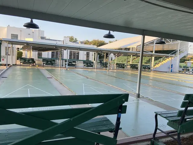 Marked shuffleboard courts with benches beneath a covered pavilion.