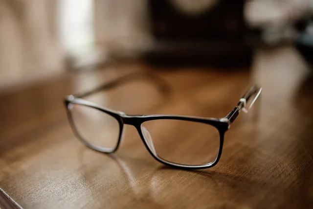 Black-framed glasses resting on a wooden surface.