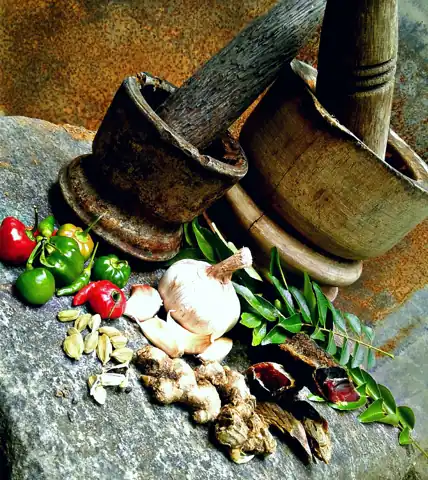 Mortars and pestles beside garlic, ginger and chillies.