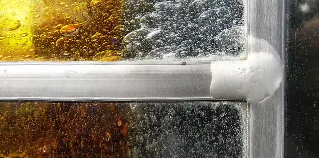 A close view of a soldered joint between the metal strips of a stained-glass panel.