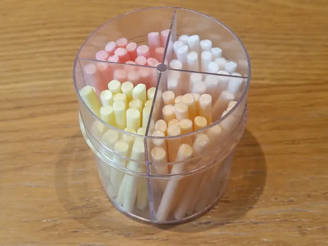 Coloured candy sticks arranged in a divided transparent container.