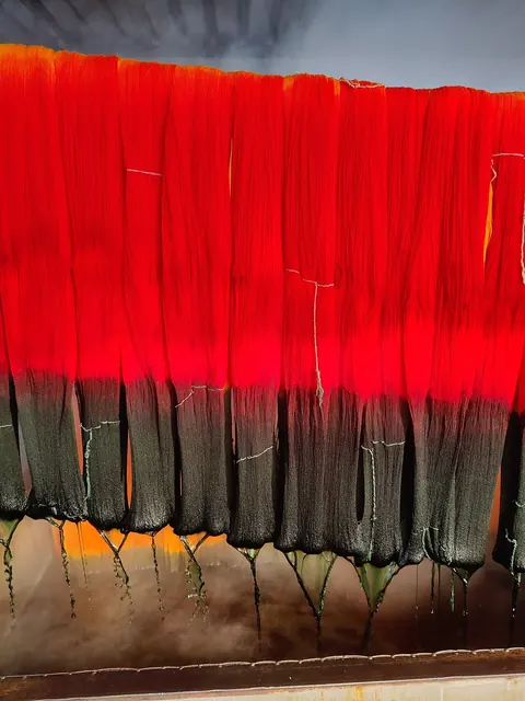 Skeins of yarn hanging after being dyed in red and dark colours.