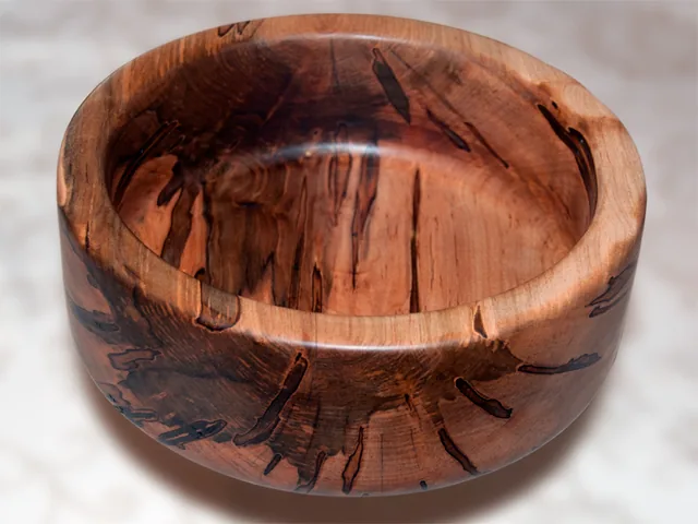 A turned wooden bowl showing the grain of ambrosia maple.