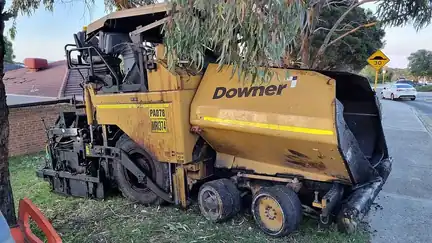 An asphalt paving machine parked beside a road.