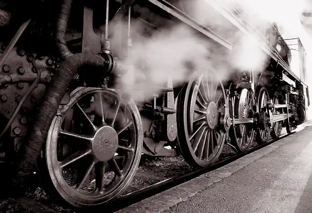 Steam drifting past the wheels of a preserved locomotive.