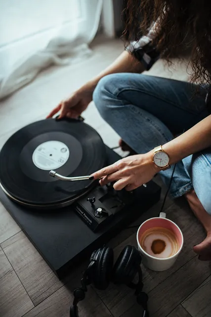 Hands placing a vinyl record on a turntable.
